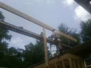 Carpenter setting a ridge beam over a new addition frame — Ice Dam Removal by Roofing Brothers in Starkville