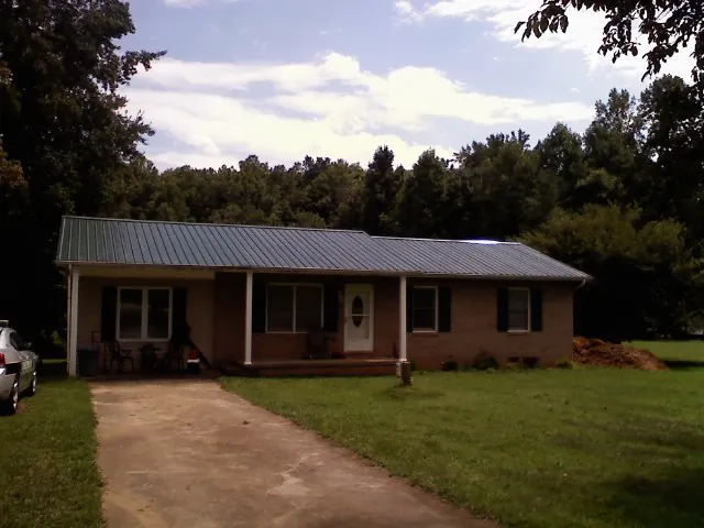 Dark green metal roof on a brick ranch with a covered porch in Starkville