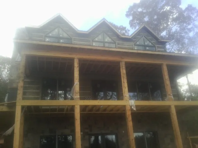 Dormers and porch framing on a large log home under construction — Roof Coating work by our crew in Starkville
