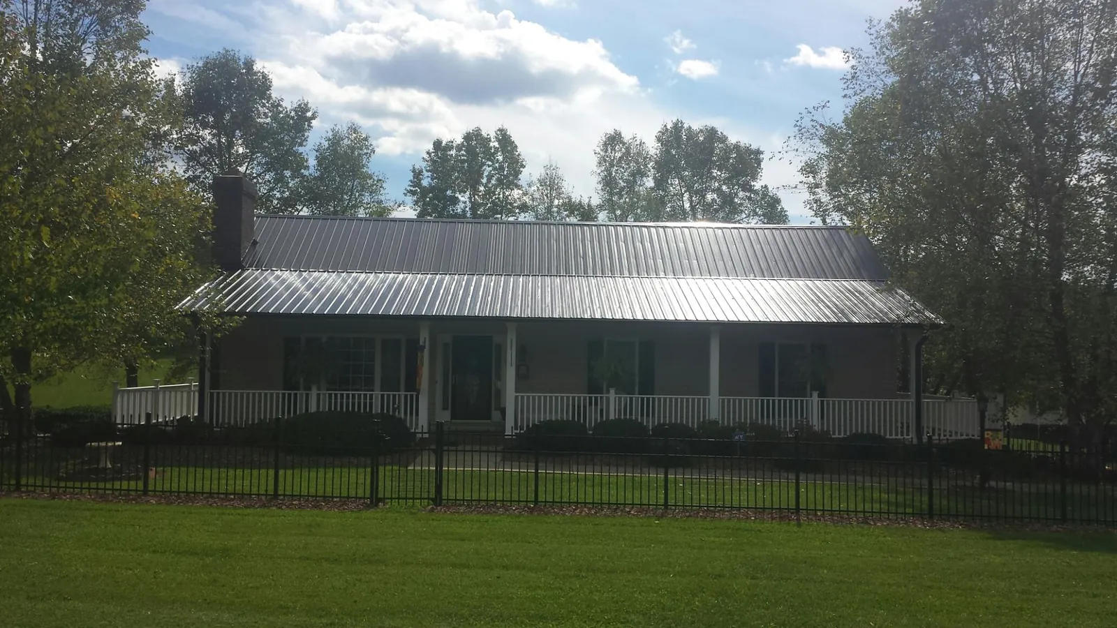 Gray metal roof on a brick ranch with a full width front porch — Gutter Guard Installation work by our crew in Starkville