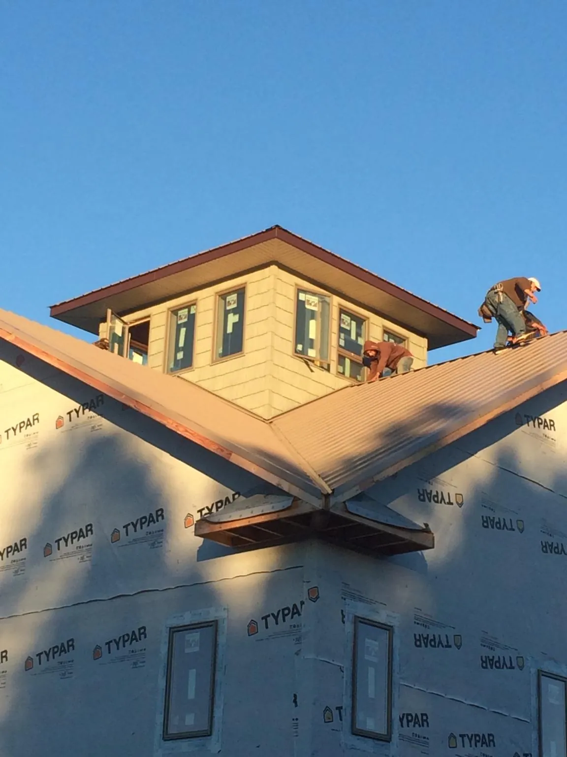 Roofers working around a rooftop cupola on a new metal roof at sunset — Roof Waterproofing in Starkville by Roofing Brothers